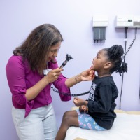Dr. Faria Abdullah checking the mouth and tonsils of little girl in ULPS Clinic